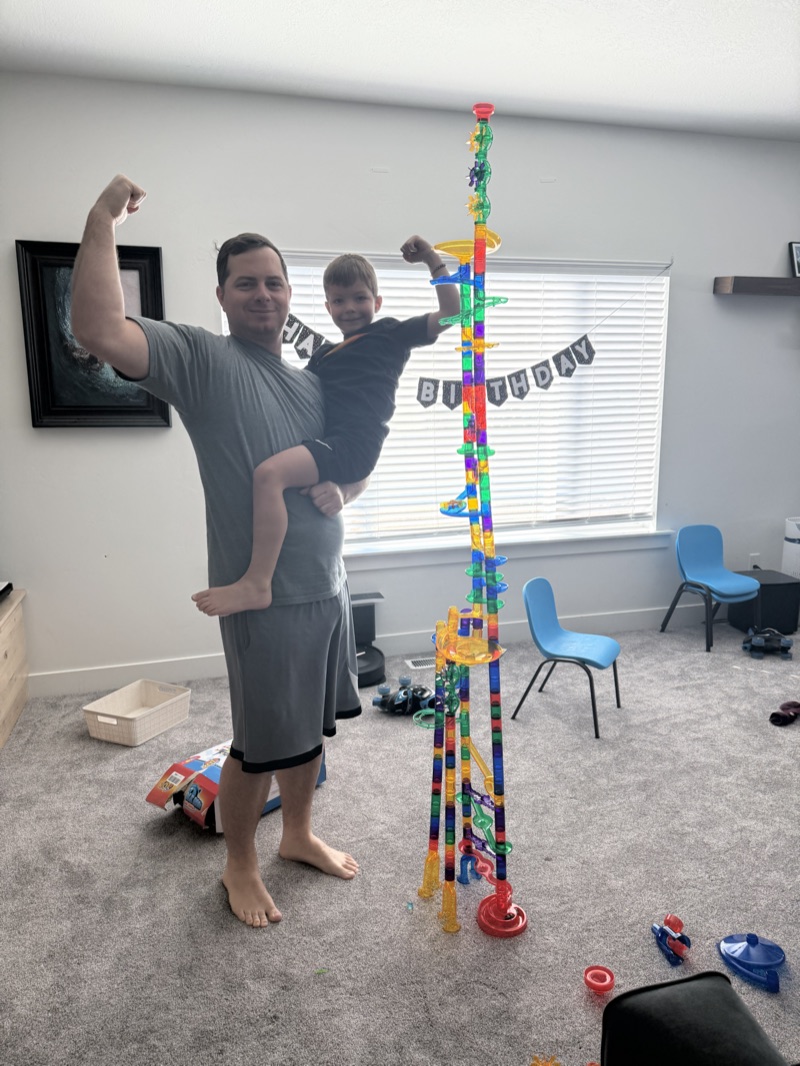 Matt holding Ollie beside a tall block tower