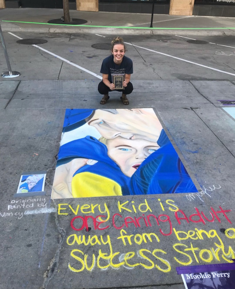 Mookie beside a large chalk mural drawn on the pavement