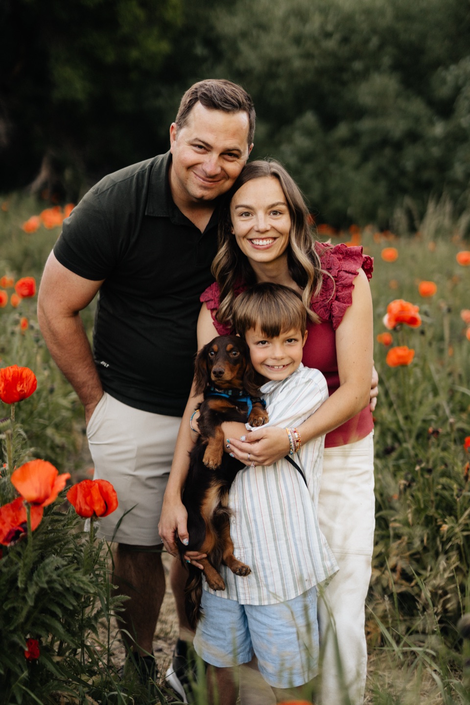 Matt, Mookie, Ollie and their dachshund standing together in the poppy field